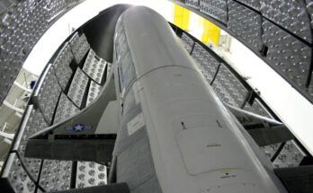 a winged space plane stands up inside its protective fairing before being sealed up for launch