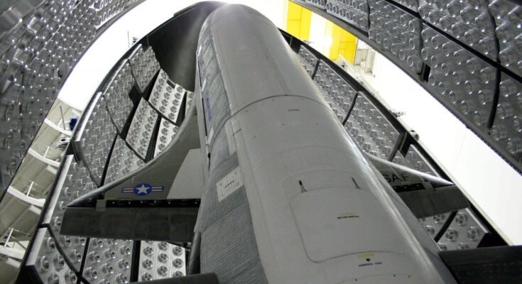 a winged space plane stands up inside its protective fairing before being sealed up for launch