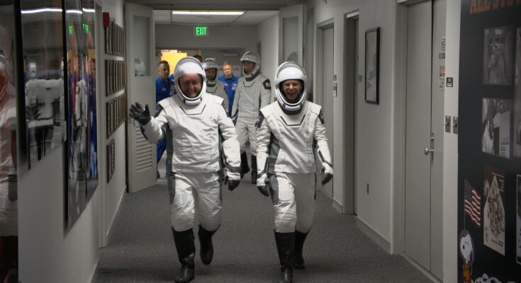 Astronauts walking down hall.