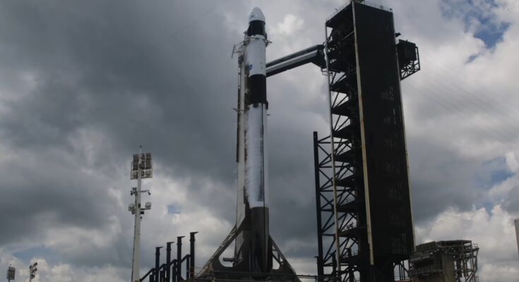 dark clouds in the sky above a white rocket upright on a launch pad