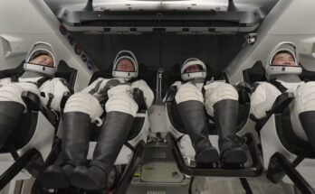 four astronauts in white spacesuit recline inside a white spacecraft cabin