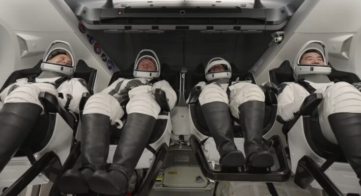 four astronauts in white spacesuit recline inside a white spacecraft cabin