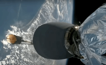The Earth is seen in the background, a cylinder is seen falling toward it, and in the foreground there is shiny material connected to what seems to be an engine.