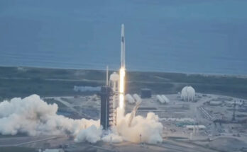 A rocket seen shooting upward with a coastline in the background.