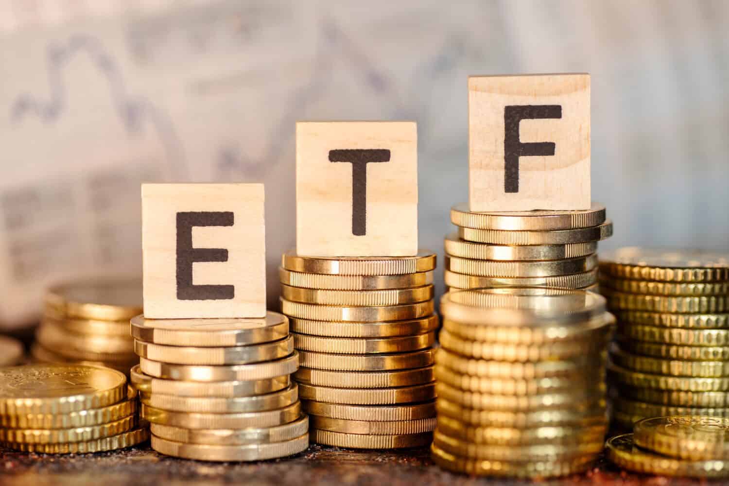 Varias pilas con monedas y términos de ETF y gráfico de precios de acciones.