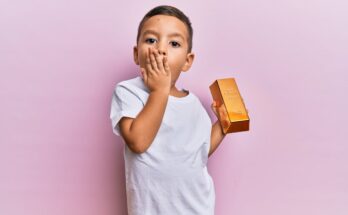 Toddler holds a gold bar.
