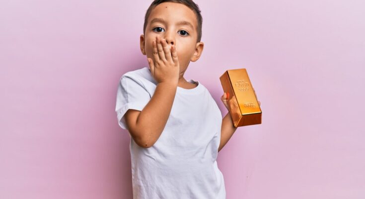 Toddler holds a gold bar.