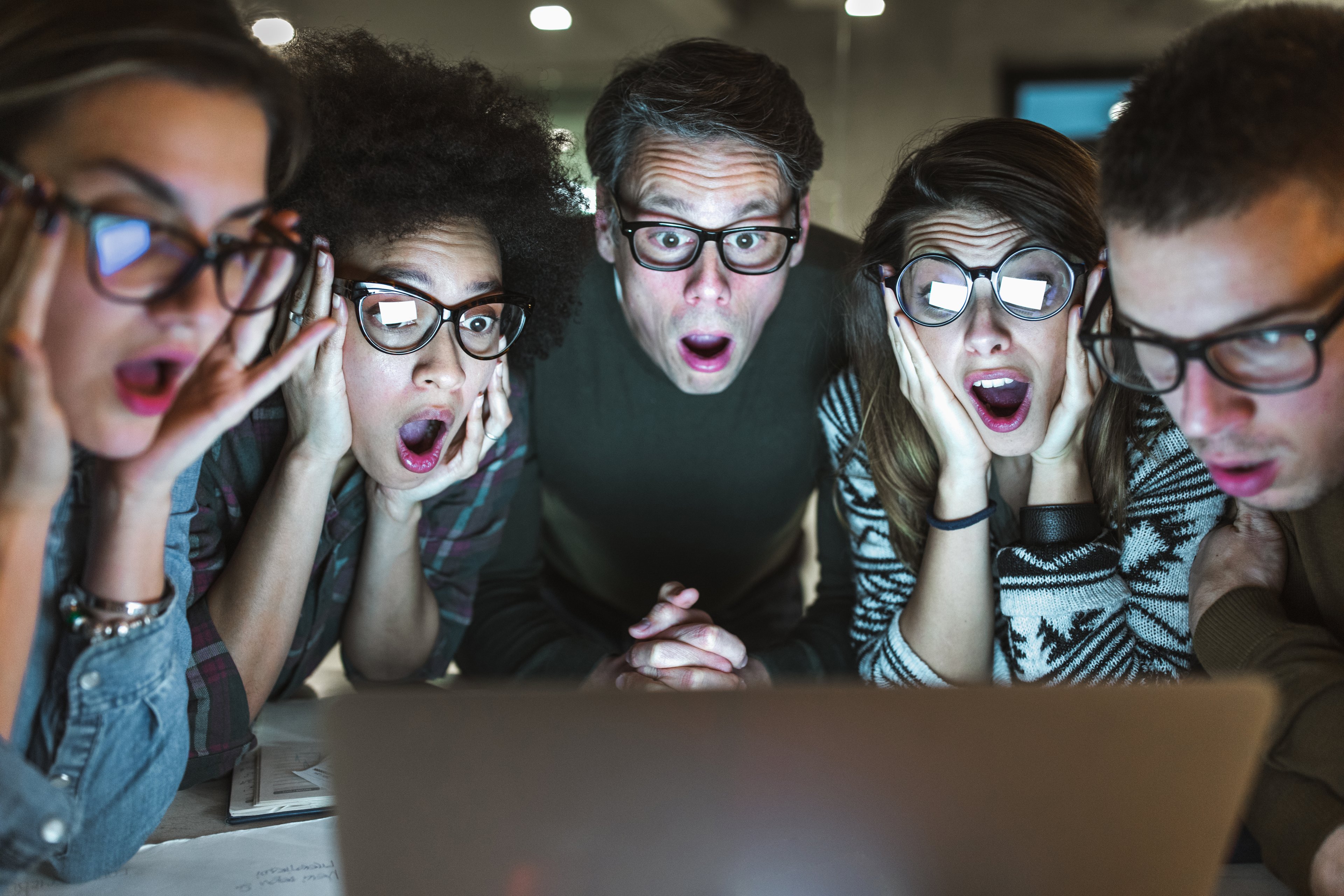Un grupo de personas sorprendidas mirando la pantalla de una computadora.