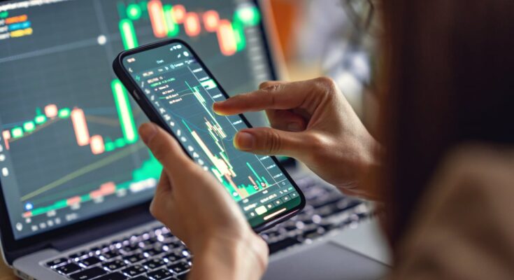 A person analyzing a price chart on a laptop and a smartphone.