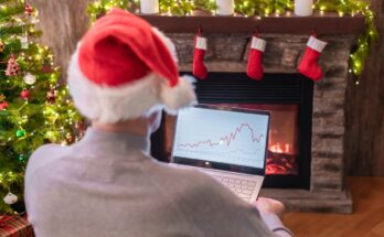 Holiday investor with laptop in front of fireplace.