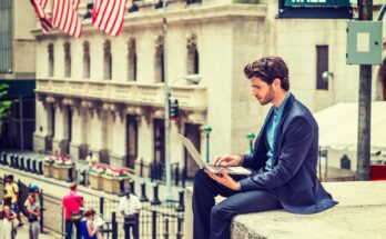 Trader with laptop on Wall Street.
