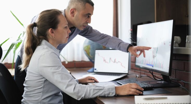 Two people looking at chart on computer.
