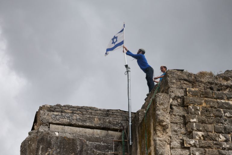 Los colonos israelíes colocan una bandera israelí en un edificio, el día del restablecimiento del asentamiento de Sa-Nur, que fue evacuado como parte de la retirada israelí de 2005, en Sa-Nur, en la Ribera Occidental ocupada por Israel, el 19 de abril de 2026. REUTERS/Shirim D TOREMSOF