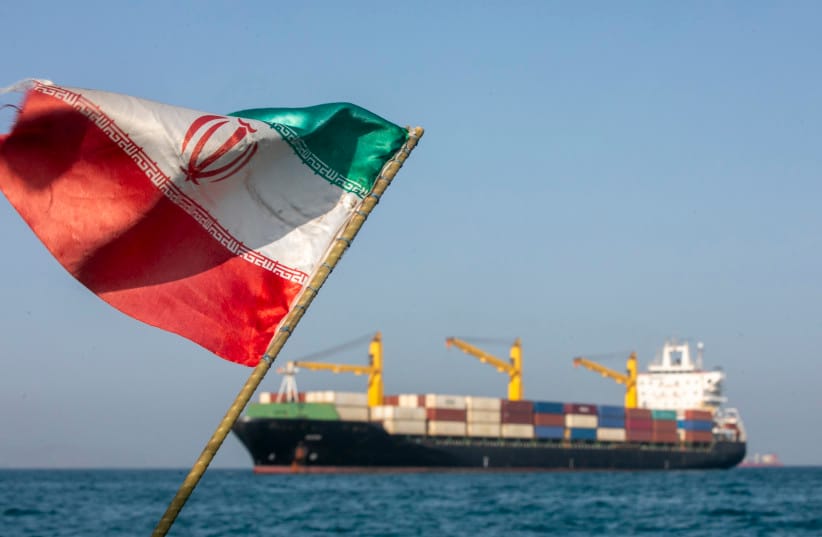 Una bandera iraní ondea al viento mientras los barcos permanecen anclados en el Estrecho de Ormuz el 16 de mayo. Las negociaciones entre Estados Unidos e Irán sobre la apertura de esta vía fluvial crítica se han estancado en gran medida.