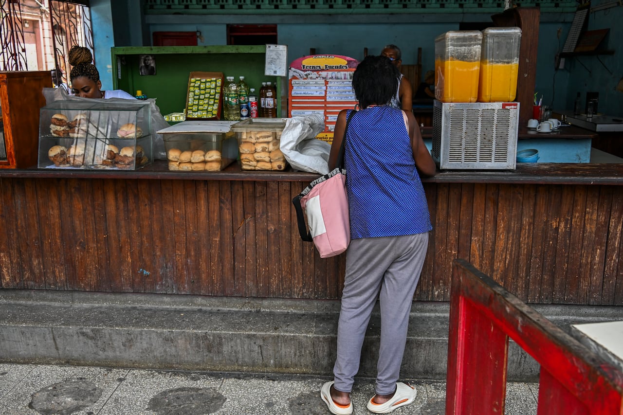 Se ve a una mujer apoyada en un mostrador mientras compra comida en una tienda privada en La Habana.